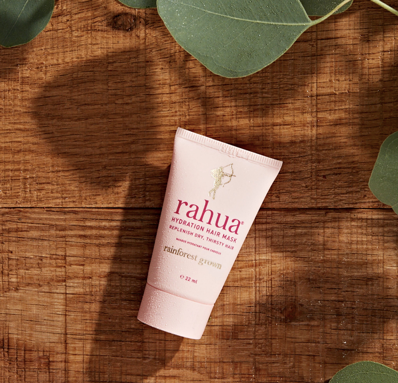 pink tube of rahua hydration hair mask on a wooden background with leaves framing the product|variant:074-oz