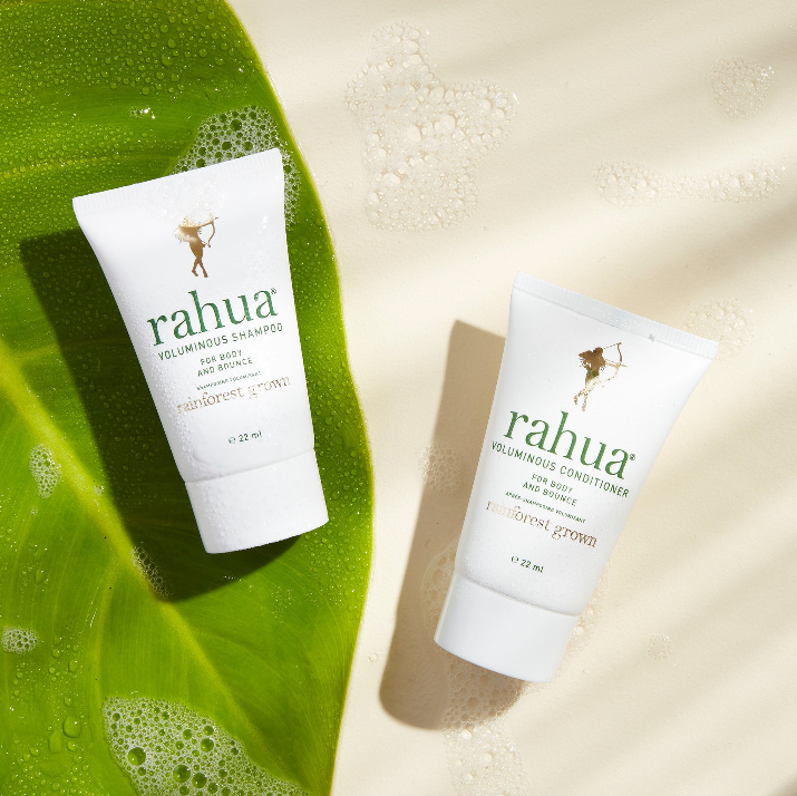 two tubes of rahua voluminous shampoo and voluminous conditioner with a palm leaf on a soapy beige background|variant:074-oz